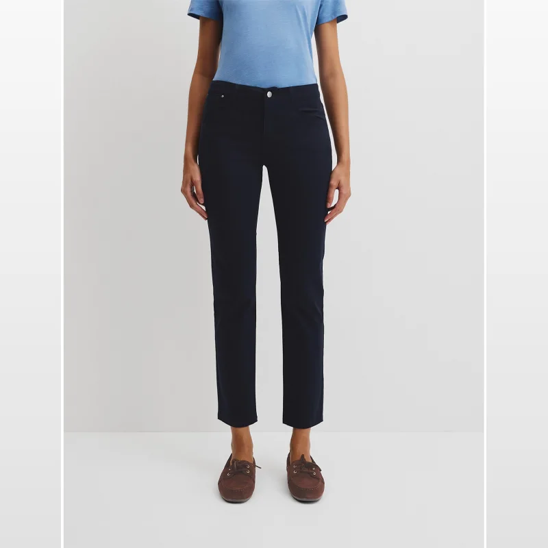 Woman wearing navy Country Road sateen jeans with a slim leg and low rise silhouette, paired with a blue t-shirt and brown loafers.