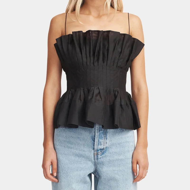 Woman wearing a black Hansen & Gretel Irvine top with a straight neckline, pleated detailing, and rouleau straps, paired with light wash jeans.