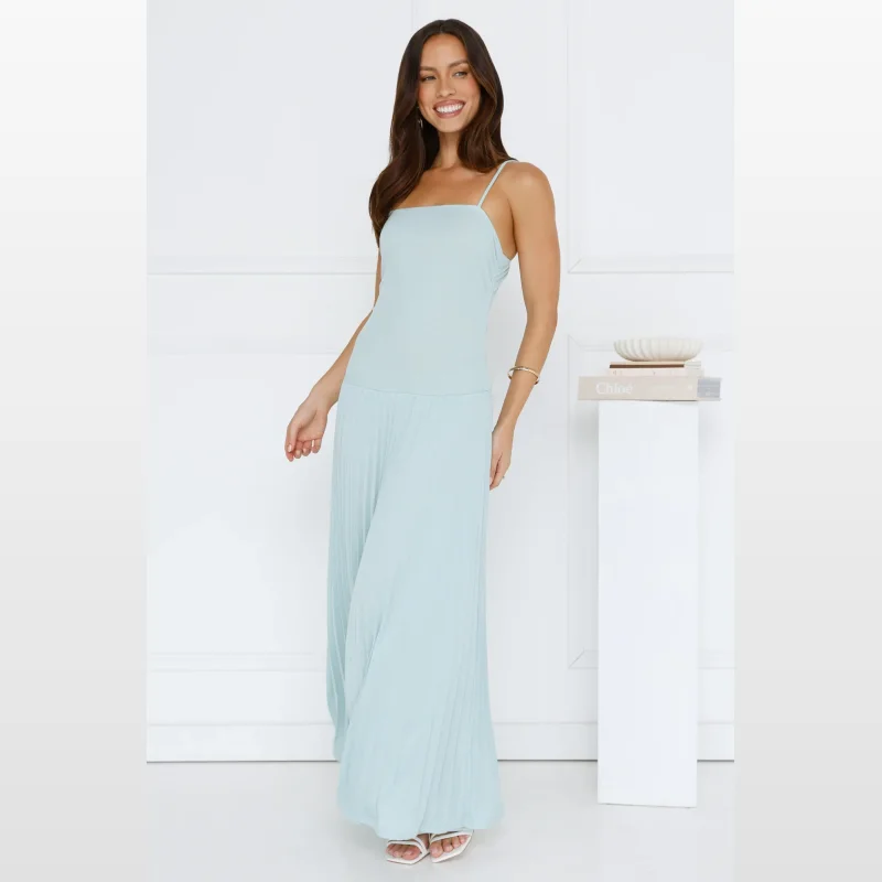 Woman wearing a sage green Lillian maxi dress with a ribbed texture and pleated skirt, standing against a white background.