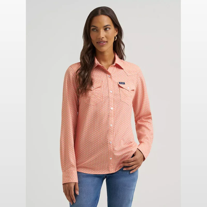 Woman wearing a coral pink long-sleeved Wrangler Aria Performance Shirt with a small white floral pattern and two chest pockets.
