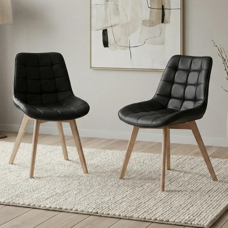 Two black faux leather dining chairs with tufted seats and light wood legs, placed on a textured rug.