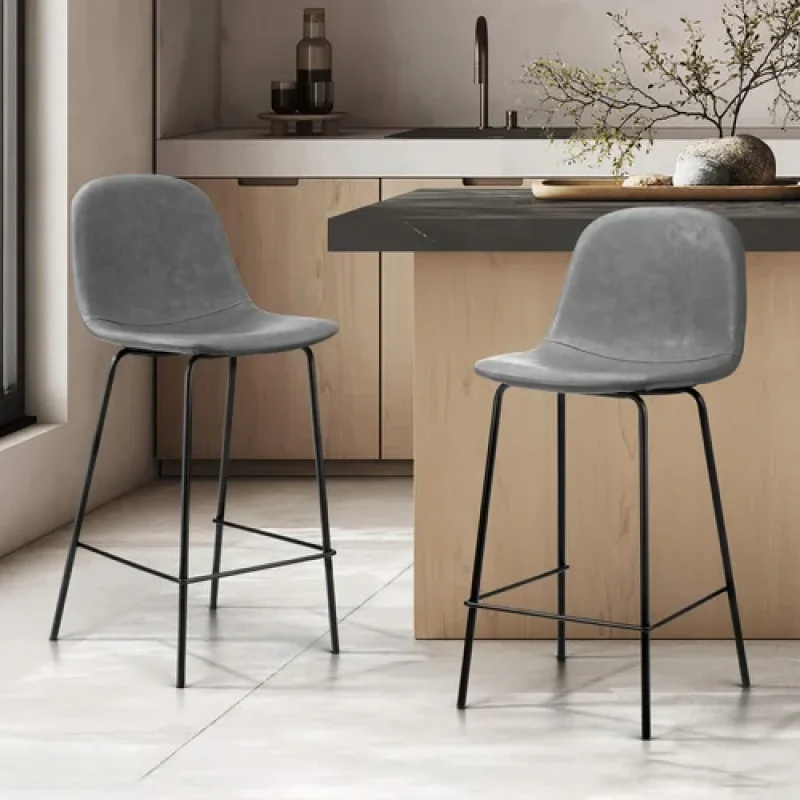 A set of two grey faux leather counter stools with black metal legs, positioned in a modern kitchen setting.