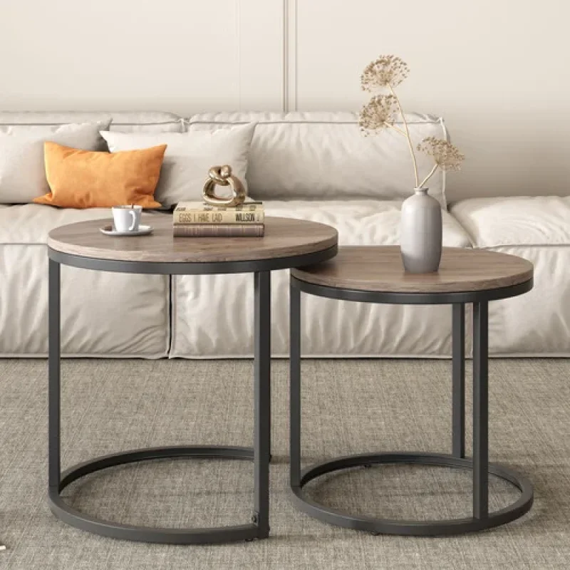 A set of two round nesting coffee tables with a wood-look top and black metal frames, placed in a living room setting.