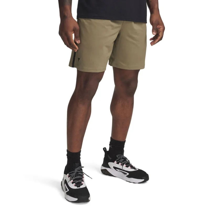 Man wearing khaki Under Armour Project Rock mesh shorts with black accents and black athletic socks and shoes.