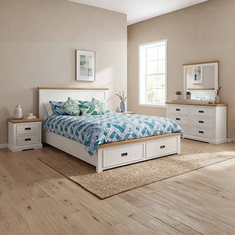 A bedroom set featuring a white and oak wood bed with storage drawers, two matching bedside tables, and a dresser with a mirror, all set against a neutral wall and wooden floor.