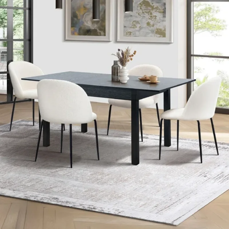 A dark extendable dining table with four white boucle chairs on a grey abstract rug in a well-lit dining room.