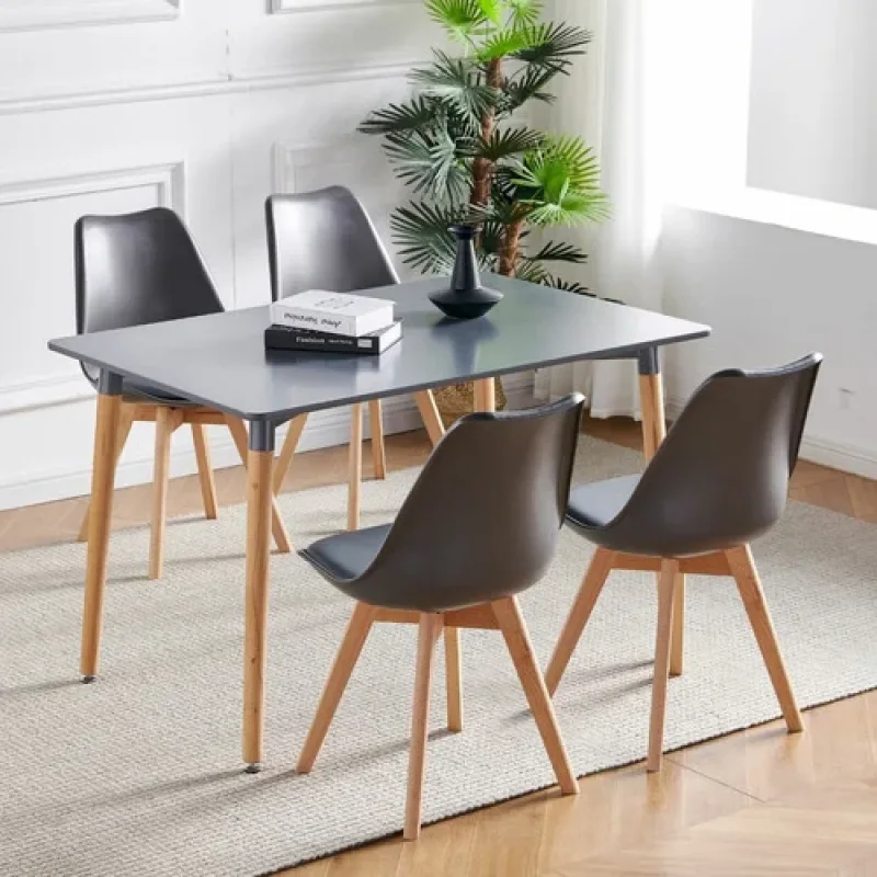 A set of four dark grey Oliver replica dining chairs with padded faux leather seats and light wood legs, arranged around a dark grey dining table.