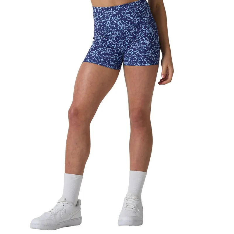 A young girl wearing blue patterned Ell/Voo Averi 3 inch short tights with a high-rise waist, white socks, and white sneakers.