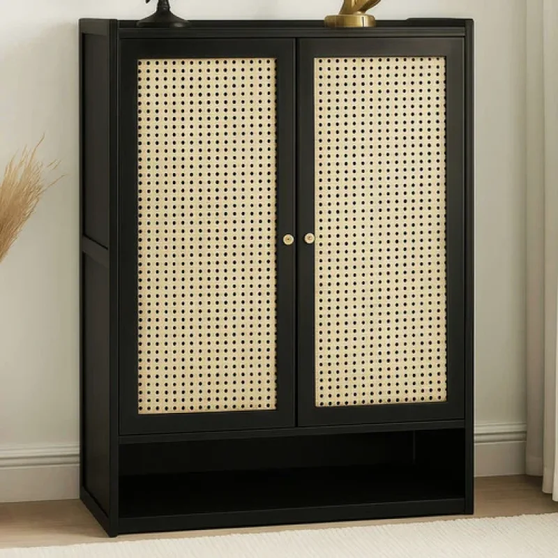 A black two-door shoe storage cabinet with cane-woven panels and a lower open shelf.