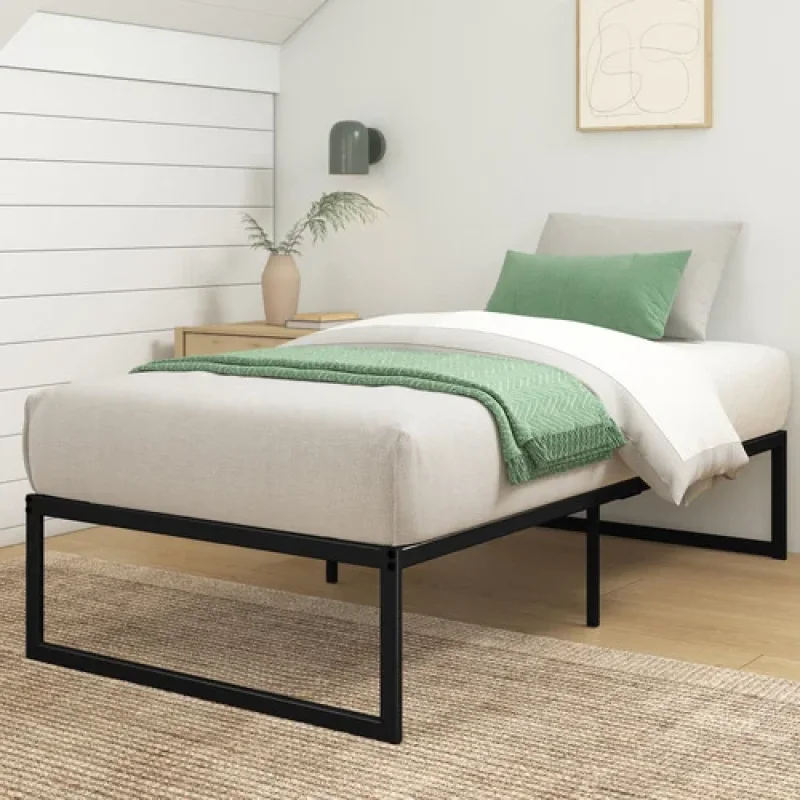 A minimalist black metal bed base with a mattress and green bedding in a bedroom setting.