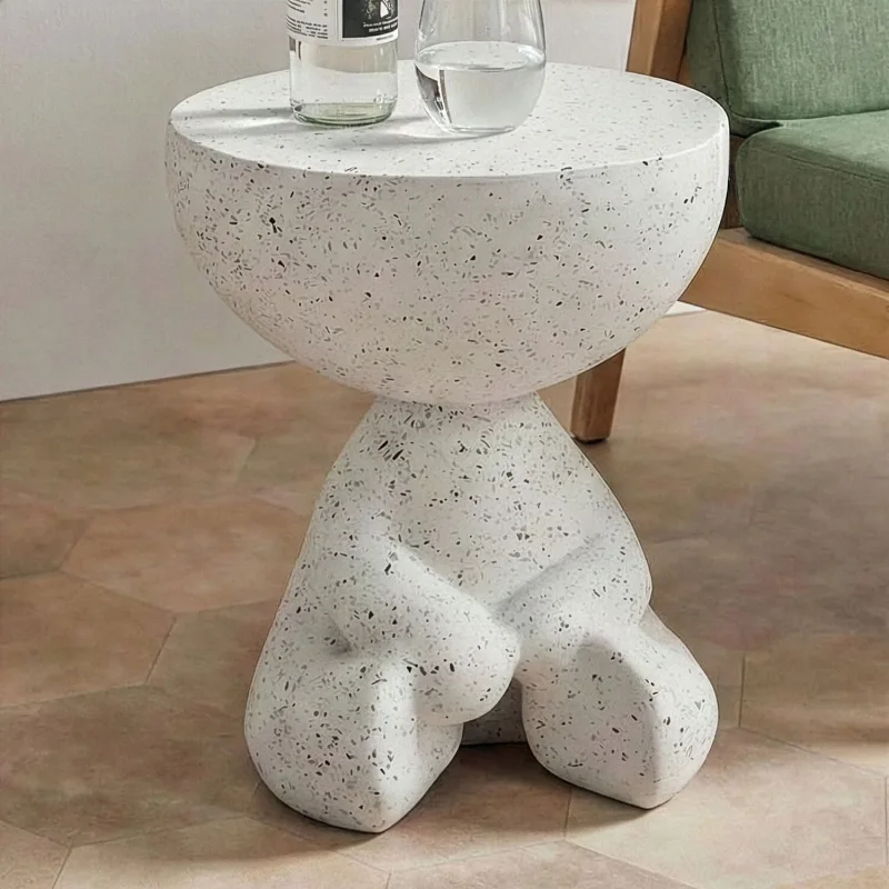 A white terrazzo side table with a rounded top and a sculptural base, featuring a unique, abstract design.