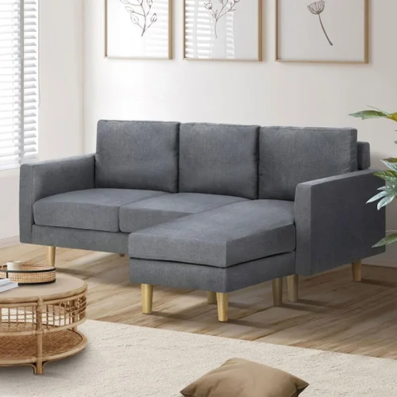 A grey three-seater sofa with a reversible chaise and wooden legs, shown in a living room setting.