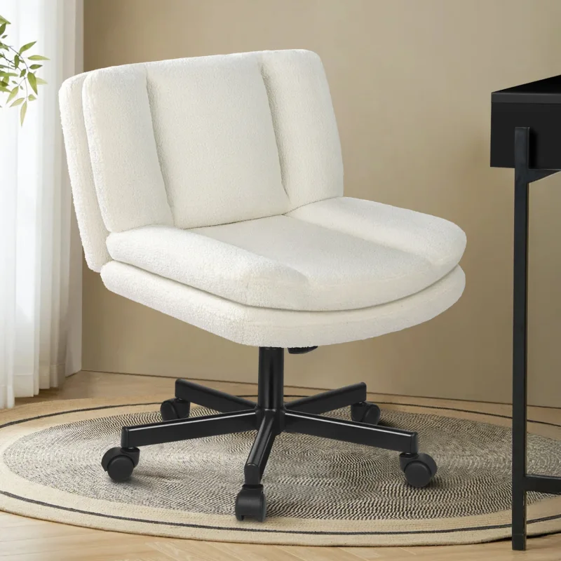 A white boucle office chair with black castors sits on a round rug next to a desk.
