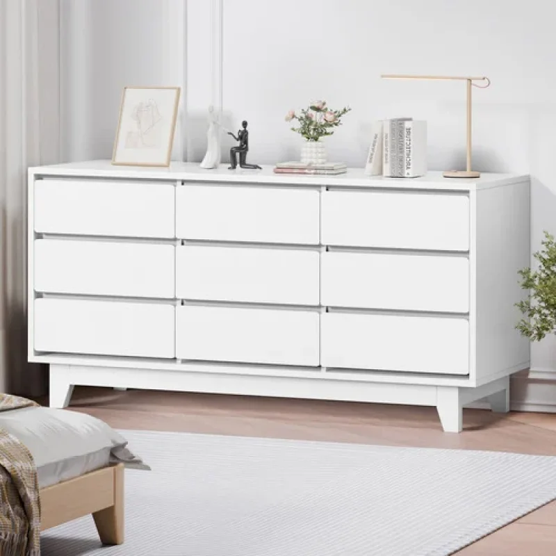 A white 9-drawer chest of drawers with a clean, modern design, featuring a melamine finish and tapered legs, placed in a bedroom setting.