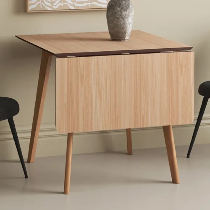 A natural wood Larsen extendable dining table with drop leaves down, featuring tapered legs and a light oak veneer finish.