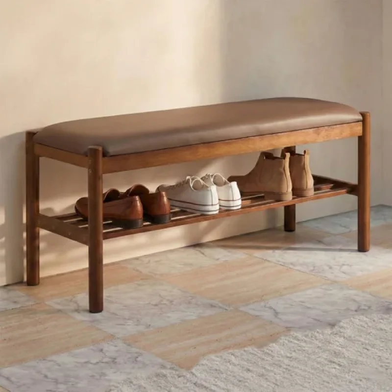 A 100cm Idris shoe storage bench with a brown padded seat and two slatted shelves holding various shoes, made from bamboo.