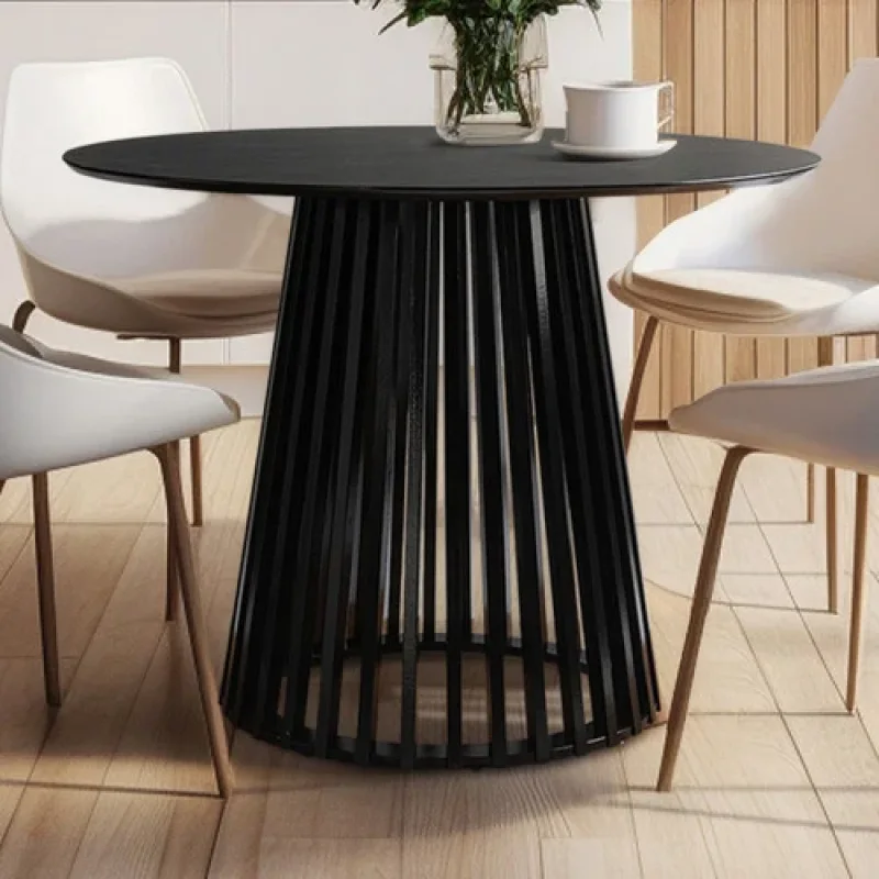 A black round dining table with a slatted pedestal base, surrounded by white chairs in a dining room setting.