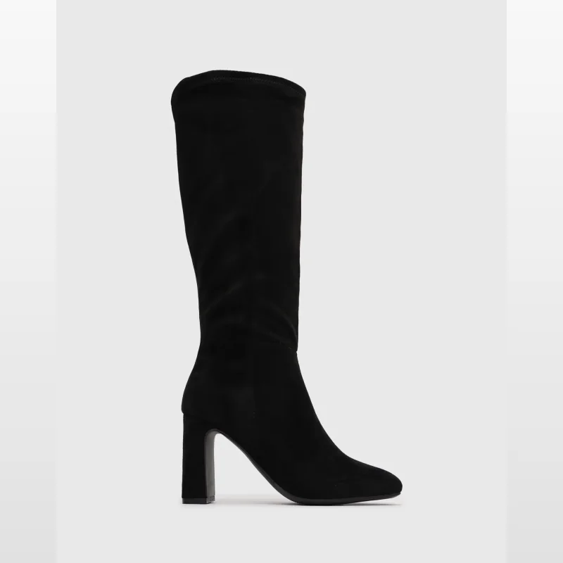 A black suede knee-high boot with a chunky block heel, presented against a plain grey background.