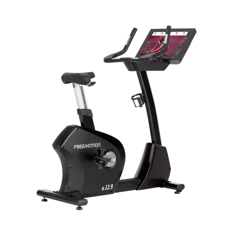 Black FreeMotion U22.9 commercial upright exercise bike with a large 22-inch HD touchscreen display showing an interactive workout.