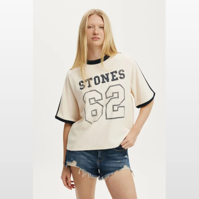 Woman wearing a cream-coloured oversized raglan t-shirt with 'STONES 62' graphic print and navy trim on the neckline and sleeves.