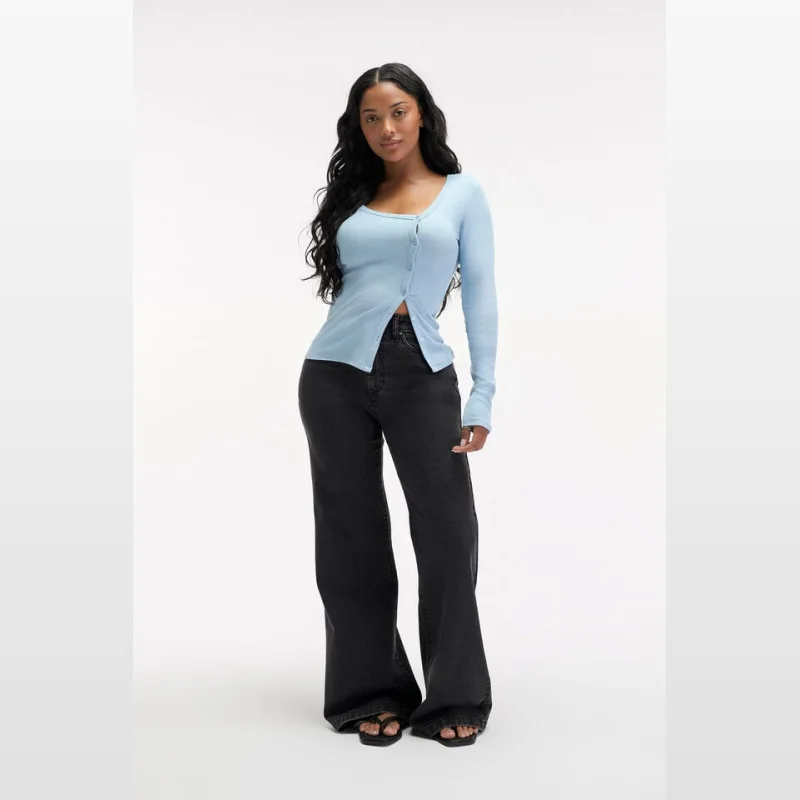 Woman wearing light blue long-sleeved button-up top and dark wash wide-leg jeans.
