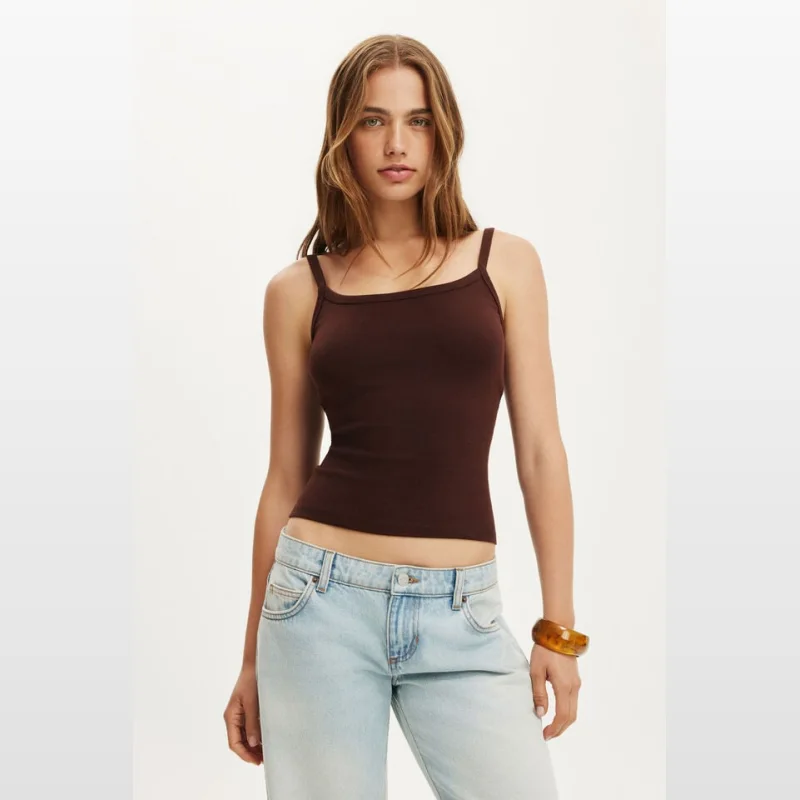 Woman wearing a dark brown fine rib scoop neck cami with thin straps and light wash denim jeans.