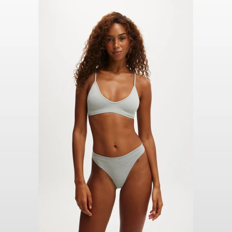 Model wearing a light grey seamless triangle padded bralette with adjustable straps and a V-neckline.