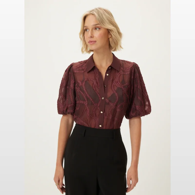 Woman wearing a burgundy sheer embroidered puff sleeve blouse with a classic collar and button-through front.