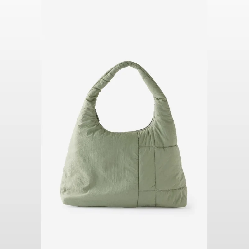 A light green, padded slouch gym bag made of nylon with a single shoulder strap and a quilted panel detail.