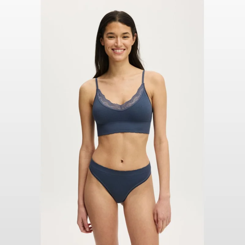 Woman wearing a blue seamless longline bralette with lace trim and matching bikini briefs.