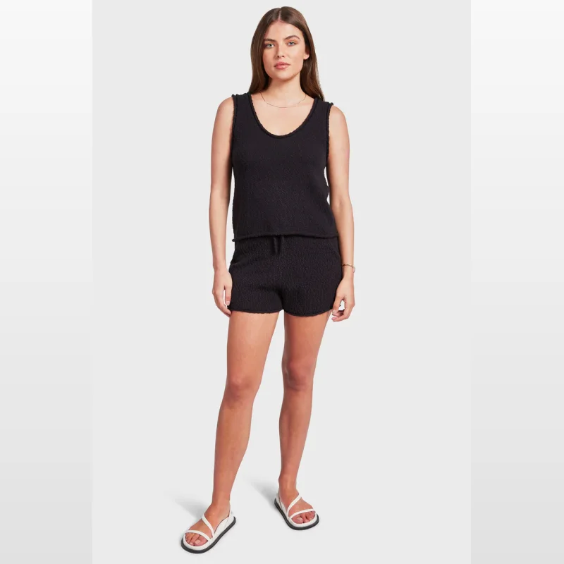Woman wearing black Academy Brand Daisy Boucle Knit Shorts with a matching tank top and white sandals.