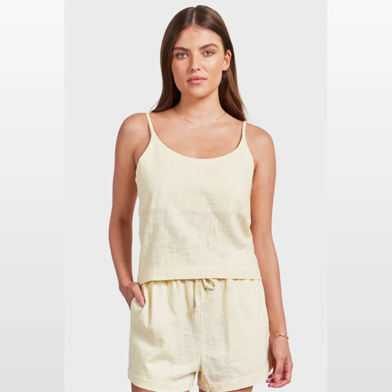 Woman wearing a pale yellow, textured cotton camisole top with adjustable straps.