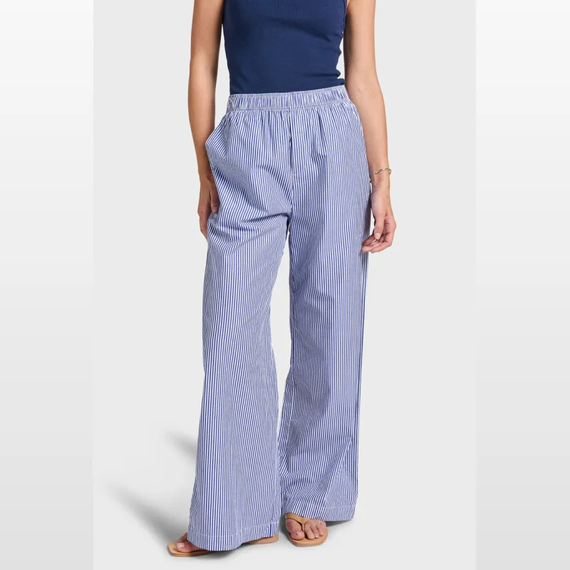 Woman wearing Academybrand Alma Stripe Poplin Pants, featuring a blue and white vertical stripe pattern, wide legs, and an elastic waistband.