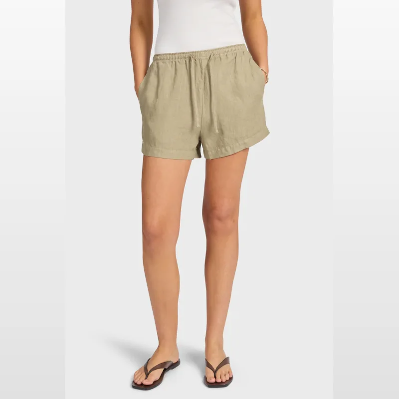 Woman wearing Academybrand Riviera Linen Shorts in a light khaki colour, featuring an elastic waistband and drawstring.