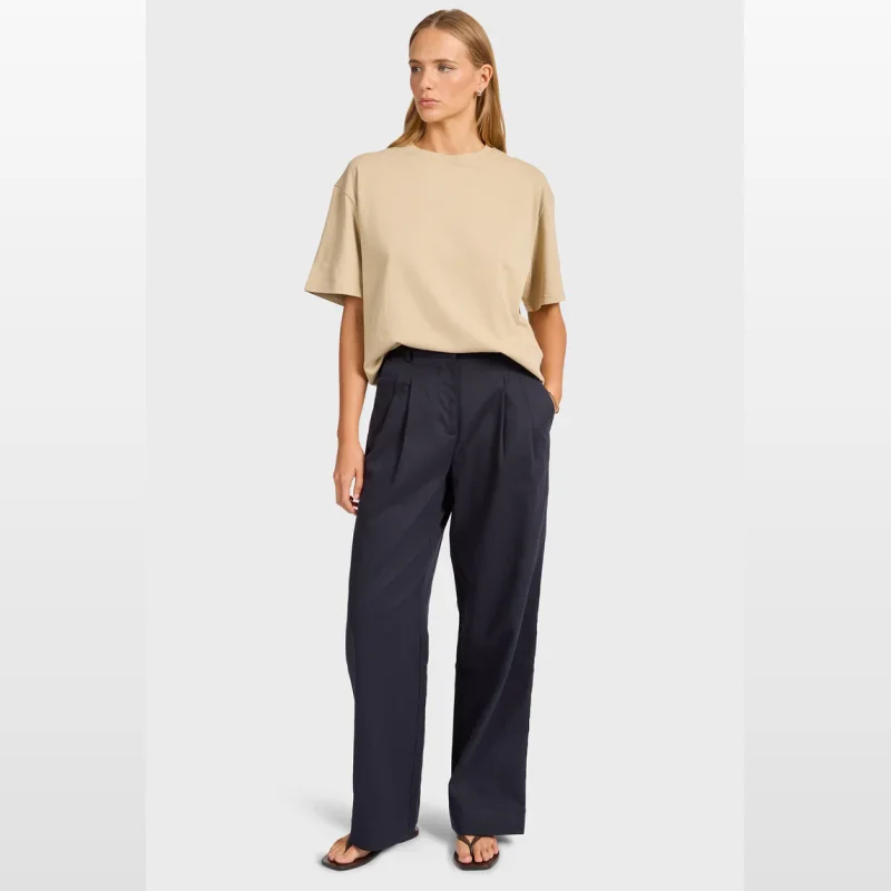 Woman wearing Academy Brand Monroe Pleated Pant in navy, a high-rise, wide-leg style with double pleats and side pockets.