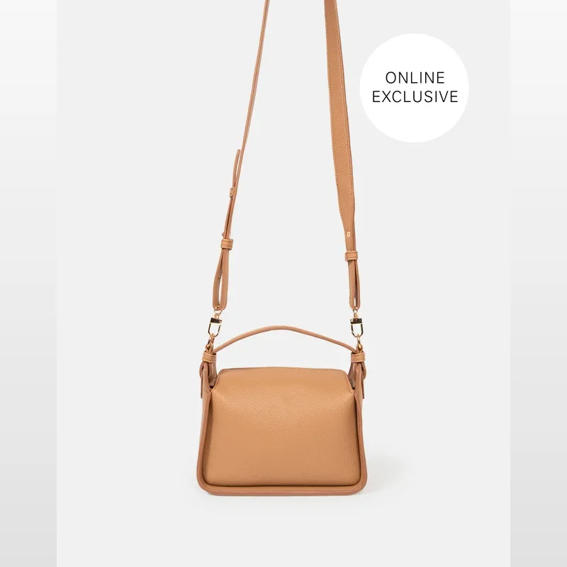 Tan textured vegan leather handbag with a top handle and adjustable shoulder strap, featuring gold-tone hardware.