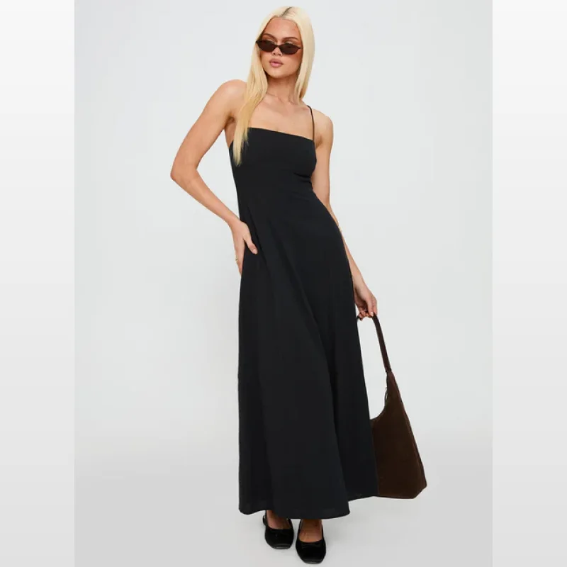Woman wearing a black spaghetti strap maxi dress with a straight neckline and an exposed back with cross tie detail.