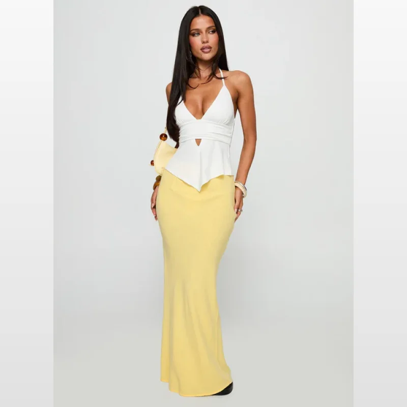 Woman wearing a lemon yellow maxi skirt with a white halter neck top.