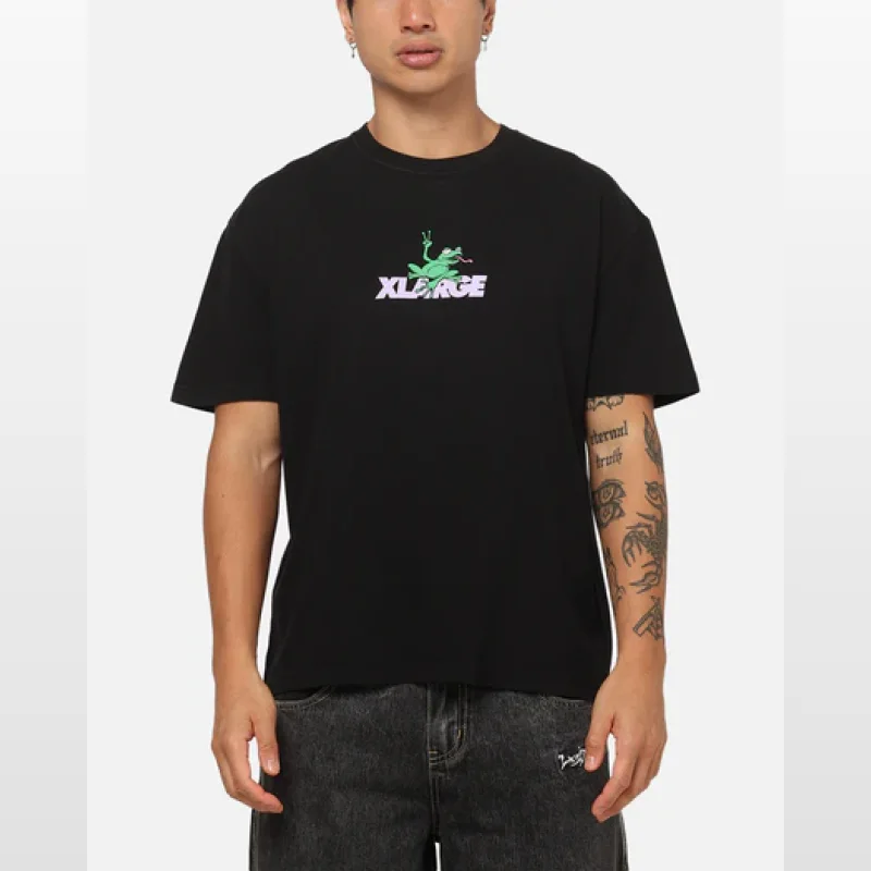 Man wearing a black X-LARGE t-shirt with a graphic of a green frog and the X-LARGE logo in purple and white.