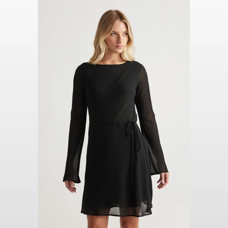 Woman wearing a black long-sleeved georgette mini dress with a high neckline and adjustable waist tie.