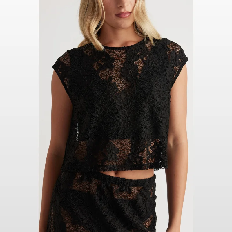 Woman wearing a black short-sleeved, round-neck, semi-sheer lace cropped top with a keyhole button closure at the back.