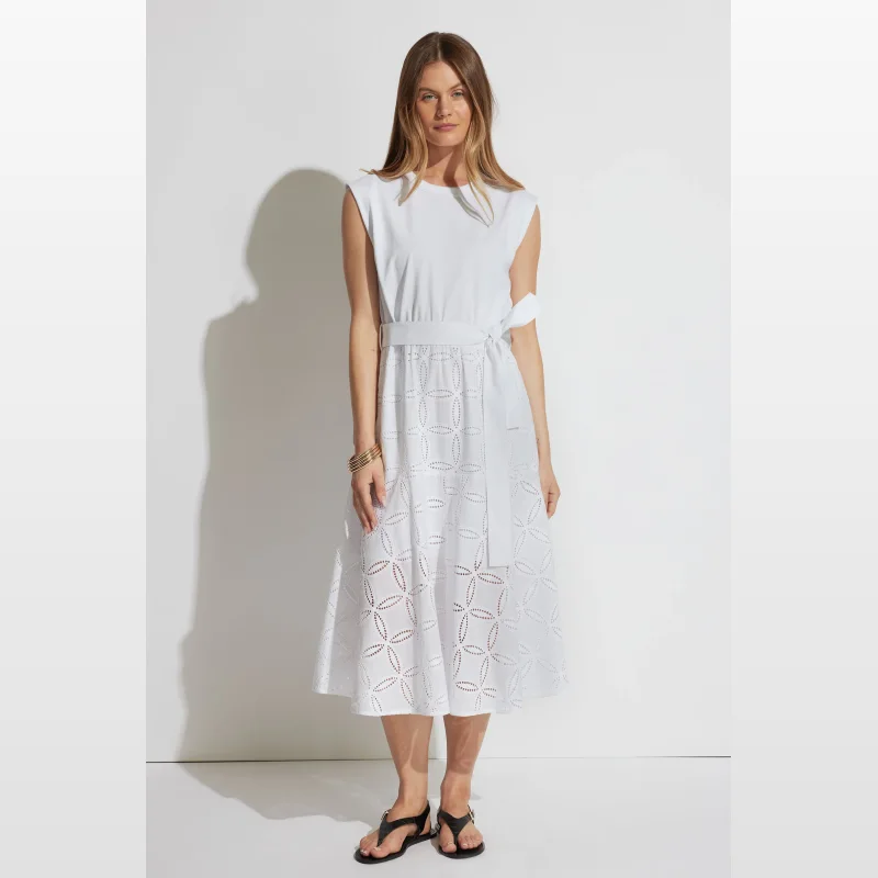 Woman wearing a white sleeveless broderie midi dress with a tie waist.