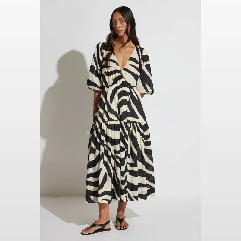 Woman wearing a black and white zebra print midi wrap dress with half sleeves and a tiered skirt.