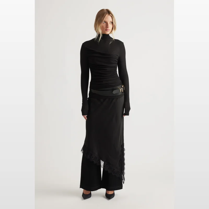 Woman wearing a black Decjuba Alicia high neck long sleeve top with gathered side seams.