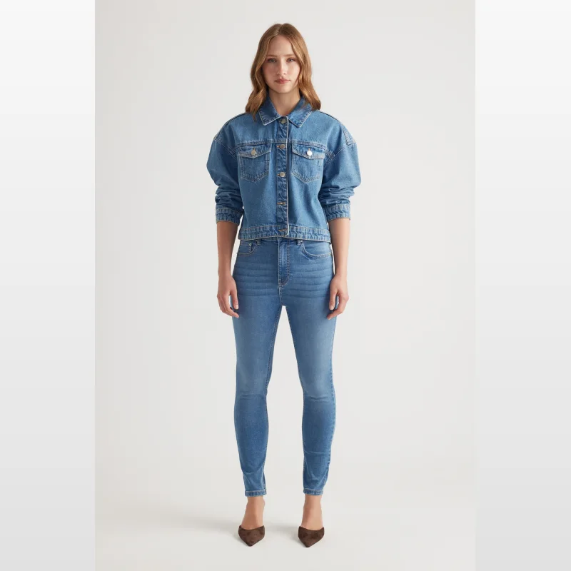 Woman wearing Decjuba Chloe Denim Skinny Jeans in a medium blue wash, featuring a high rise, skinny leg, and ankle length.