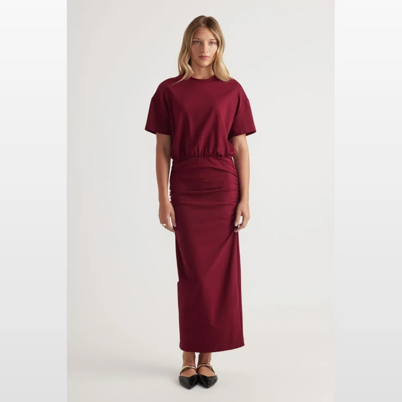 Woman wearing a maroon ruched midi dress with short sleeves and a round neckline.