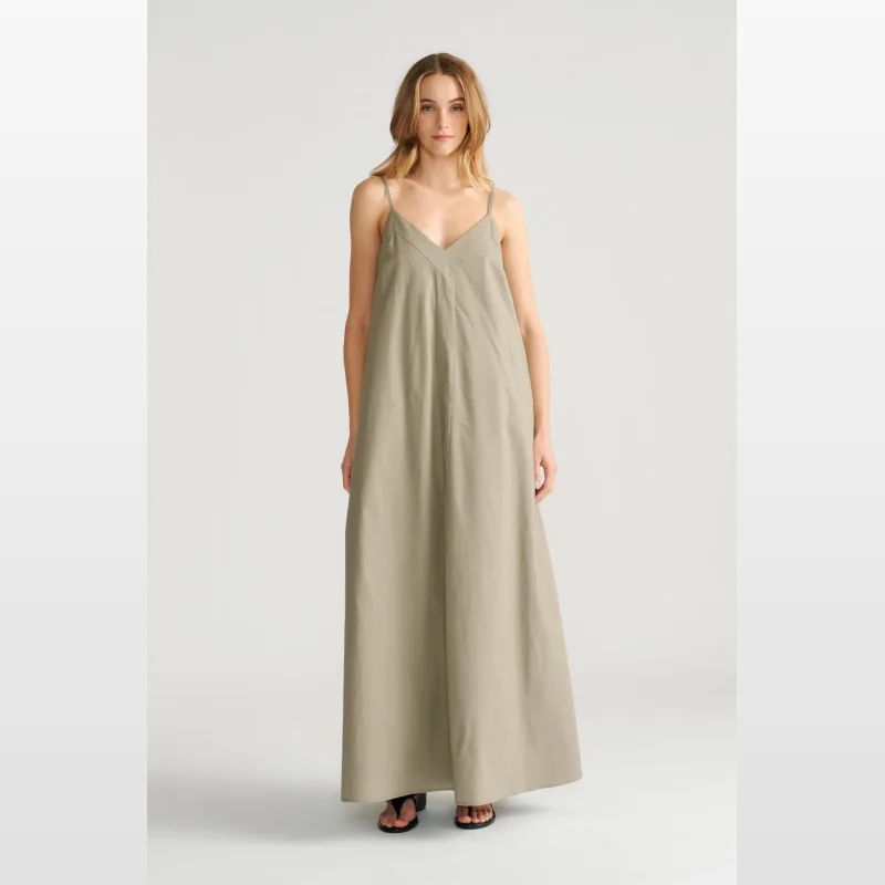 Woman wearing a sleeveless, v-neck, khaki green trapeze maxi dress by Decjuba.