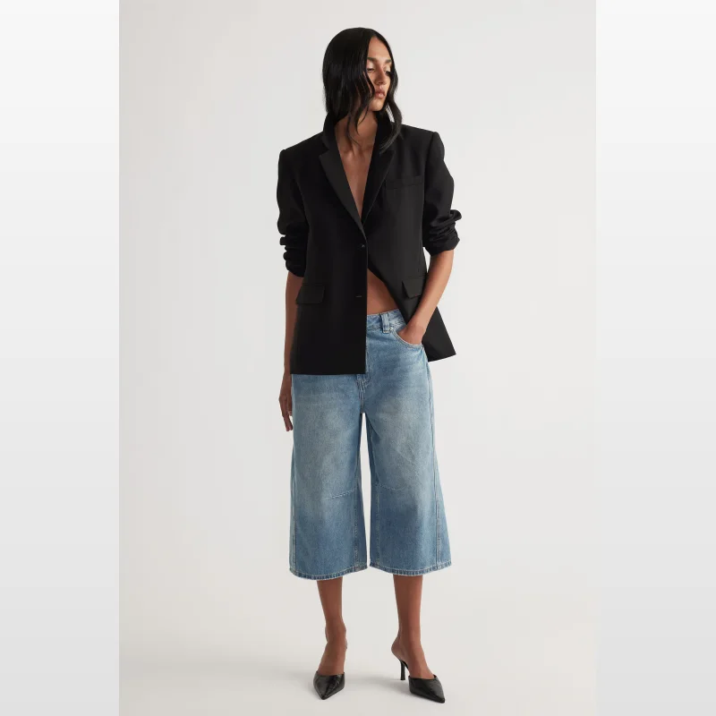 Model wearing Decjuba Lennon wide leg high rise denim jorts in a light wash blue denim.