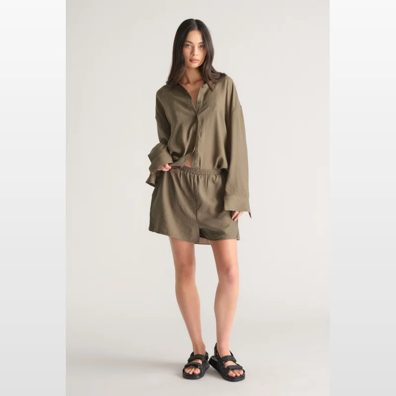 Model wearing Decjuba D-Luxe Textured Shorts in olive green, featuring an elasticated waistband and side pockets.