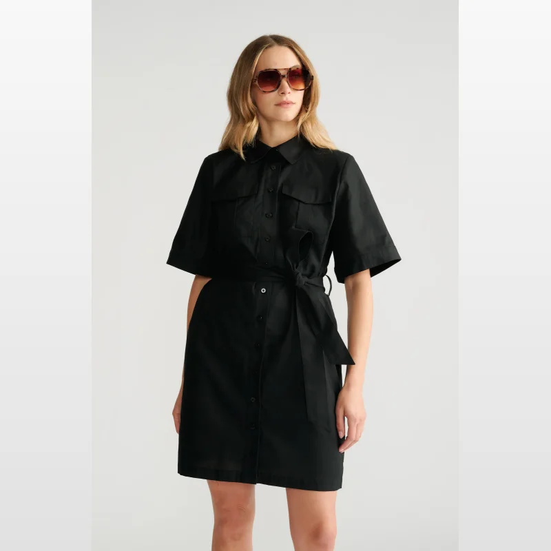 Woman wearing a black short sleeve collared mini dress with an adjustable waist tie and button-up front.